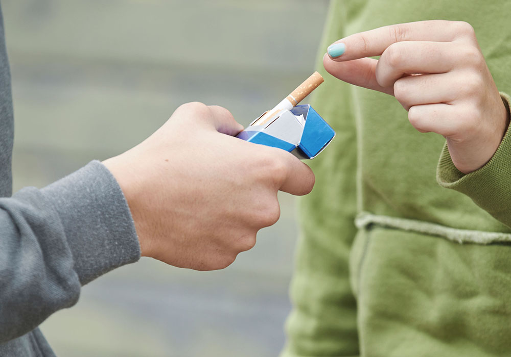 person's hand offering a cigarette to another person